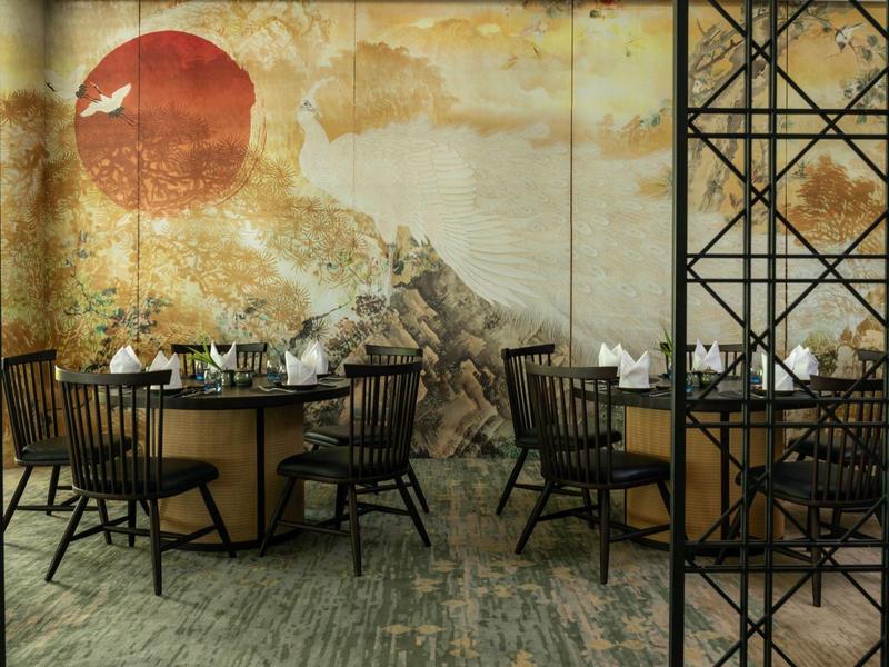 Eleganter Gastraum mit schwarzen Stühlen und runden Tischen vor einer Wand mit künstlerischem Sonnenmotiv.