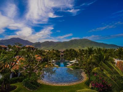 Großer Pool umgeben von Palmen und Bergen unter blauem Himmel bei sonnigem Wetter