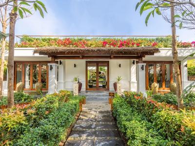 Moderner Bungalow mit Garten und Weg im tropischen Stil.