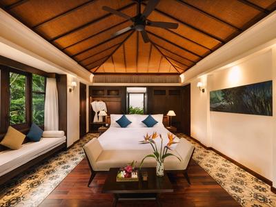 Gemütliches Schlafzimmer mit Holzbalken, großem Bett, Fensterbank und Pflanzen auf dunklem Holzboden.