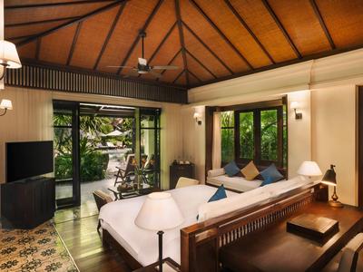 Helles Wohnzimmer mit Holzdecke, weißem Sofa, Fernseher und Glas-Schiebetüren zum Garten.