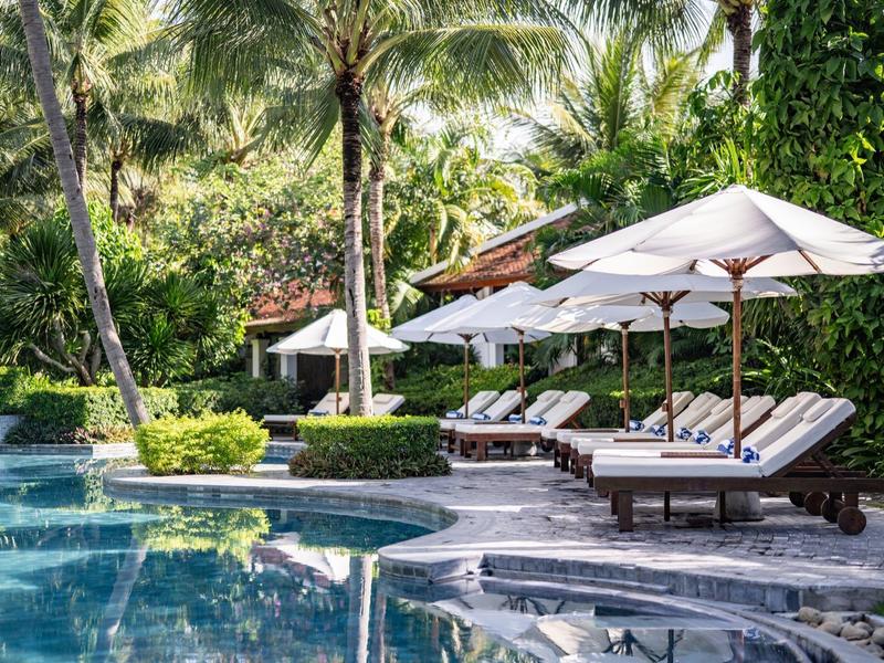 Luxuriöser Poolbereich mit Liegestühlen und Sonnenschirmen in tropischem Garten