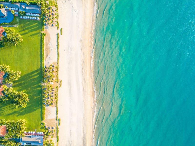 Moderner Innenhof mit Wasserspiel, großen Vasen, Holz- und Glaselementen, umgeben von grünem Pflanzenreich.