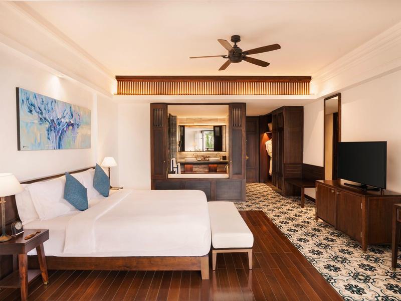 Modernes Wohnzimmer mit weißem Sofa, Holzboden, Deckenventilator und TV-Möbel in warmen Tönen.