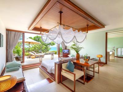 Modernes Hotelzimmer mit offenem Design, Holzmöbeln und Blick auf eine Terrasse mit Garten.