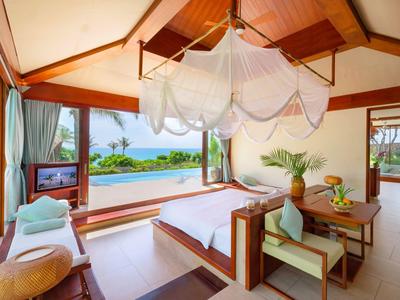 Helles Hotelzimmer mit Doppelbett, Moskitonetz und Blick auf Meer und Pool.