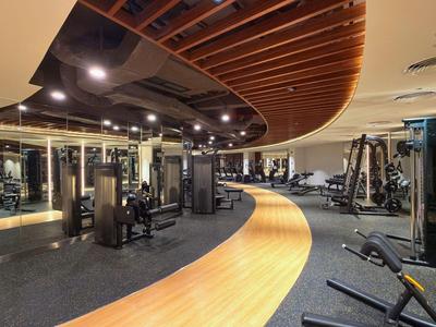 Salle de sport moderne avec parquet et équipements robustes dans un cadre hôtelier.