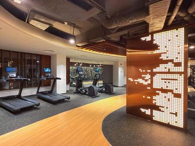 Salle de sport moderne avec tapis de course, poids et éclairage élégant dans un hôtel.