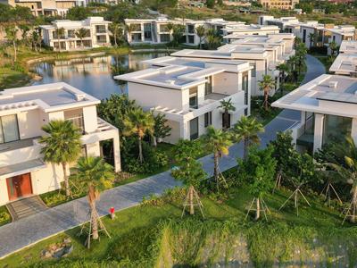 Villas blanches modernes avec piscines entourées de palmiers dans une station tropicale.
