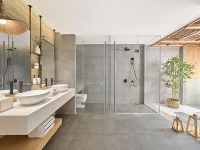 Salle de bain moderne avec doubles lavabos, grande cabine de douche et décoration végétale.