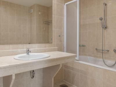 Moderne Badezimmer mit Waschbecken, großem Spiegel und Badewanne mit Duschvorrichtung.