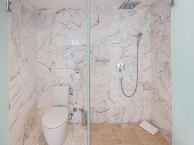 Moderne Dusche und Toilette in einem weißen Marmorbad mit Glaswand