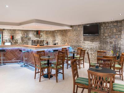 Gemütliche Bar mit Steintheken und Holzmöbeln in einem restaurierten Raum.