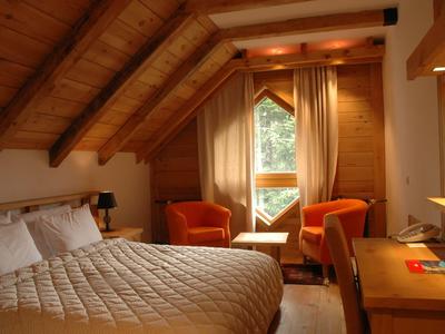 Gemütliches Schlafzimmer unter einem Dach mit Holzverkleidung und zwei Sesseln am Fenster.