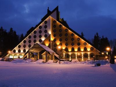 Beleuchtetes dreieckiges Hotelgebäude in verschneiter Landschaft bei Nacht