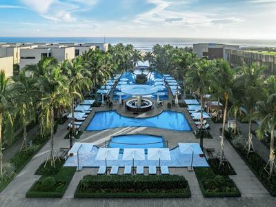 Gran piscina del hotel con varias piscinas, rodeada de palmeras y sombrillas