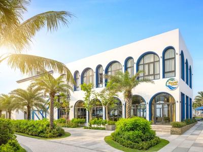 Edificio de hotel moderno con grandes arcos de ventanas y palmeras en el área exterior soleada.