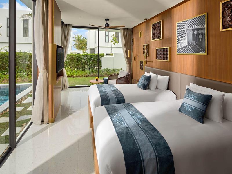 Habitación de hotel con dos camas, grandes ventanas y vista a una piscina y jardín.