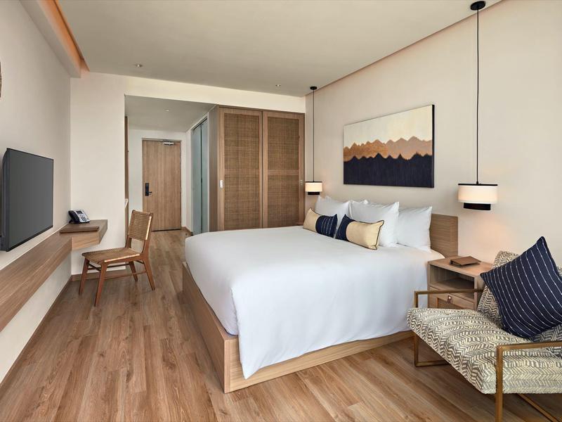 Habitación de hotel moderna con cama doble, suelo de madera y decoración elegante.