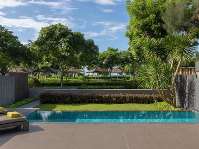 Zona de piscina moderna con tumbonas, rodeada de árboles verdes y cielo azul.