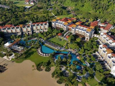 Gran complejo hotelero con varios edificios, piscina grande y acceso directo a la playa de arena.