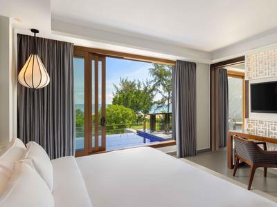 Habitación de hotel moderna con cama grande, escritorio y vista a la piscina y jardín.