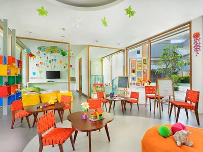 Sala de juegos colorida con varios muebles infantiles y ventanas que dejan entrar la luz natural.