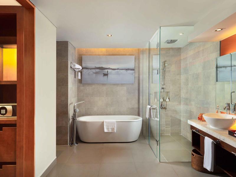 Baño moderno de hotel con bañera independiente y ducha de vidrio tipo walk-in.