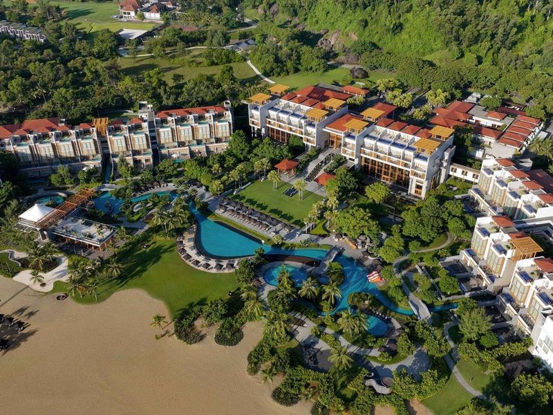 Gran complejo hotelero con varios edificios, piscina grande y acceso directo a la playa de arena.