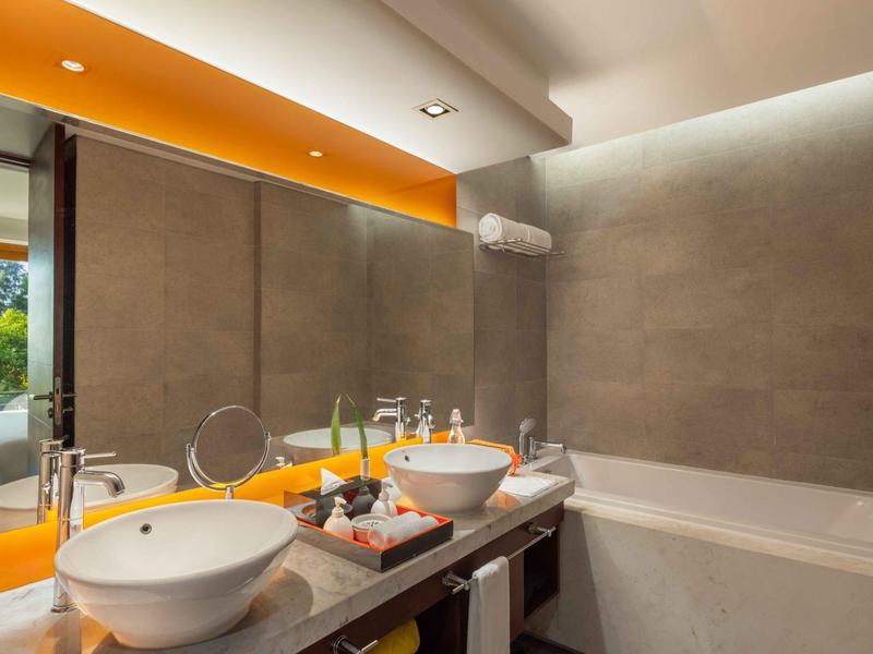 Baño moderno con doble lavabo, bañera y gran espejo con iluminación indirecta.