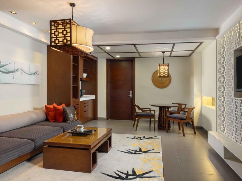 Sala moderna con sofá gris, muebles de madera y alfombra con patrón floral.