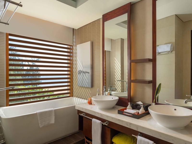 Baño moderno con bañera independiente, dos lavabos y espejo grande.