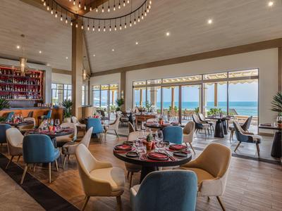 Ristorante elegante con vista mare, mobili moderni e tavoli elegantemente apparecchiati.