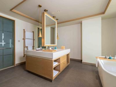 Bagno moderno con grande vasca, lavabo e armadi in legno dal design neutro.