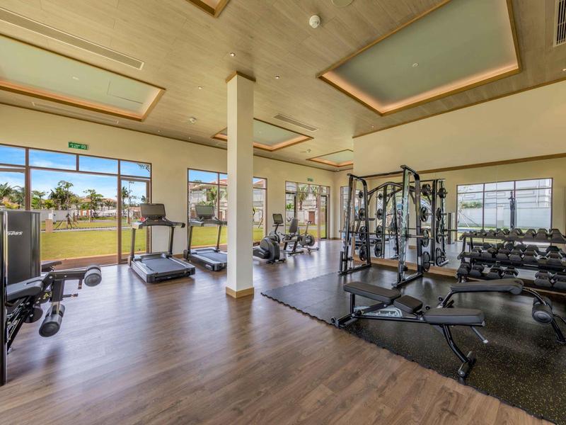 Palestra moderna con attrezzi, pesi e grandi finestre che si affacciano all'esterno.