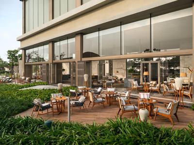 Moderner Hotelaußenbereich mit Holzterrasse, Sitzgruppen und grüner Vegetation.
