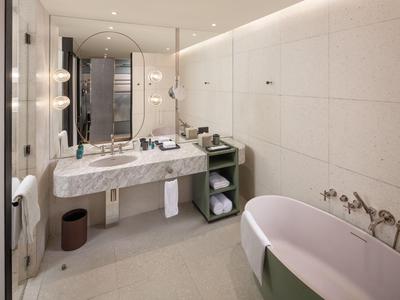 Modernes Hotelbad mit freistehender Badewanne, großem Spiegel und elegantem Waschbecken.