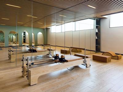 Moderner Pilates-Raum mit Holzgeräten und großen Fenstern für natürliches Licht.
