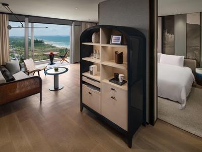 Hotelzimmer mit Sitzbereich, modernem Mobiliar und Blick auf Meer und Strand