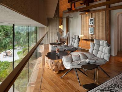 Modern eingerichteter Hotel-Lounge-Bereich mit großen Fenstern und Blick auf Garten.