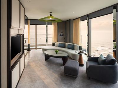 Modern eingerichtetes Hotelzimmer mit großem Fenster und Sitzbereich mit Sofa und Sesseln.