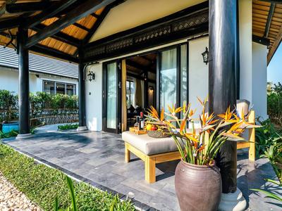 Gezellig veranda met kussenstoel en tropische planten voor een huis.