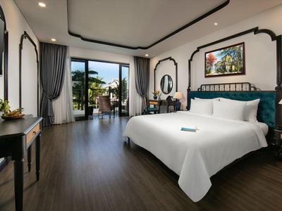 Modern hotelkamer met groot bed, bureau, balkon en uitzicht op palmbomen.