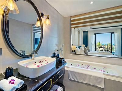 Moderne badkamer met wastafel, grote spiegel, bad en uitzicht op een terras.