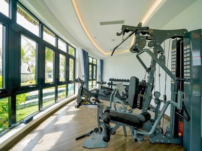 Heller Fitnessraum mit modernen Geräten und großen Fenstern mit Blick ins Grüne.