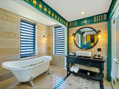 Lichte badkamer met vrijstaand bad, wastafel en decoratieve spiegel.