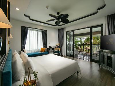 Moderne hotelkamer met balkon en uitzicht op tropische planten.