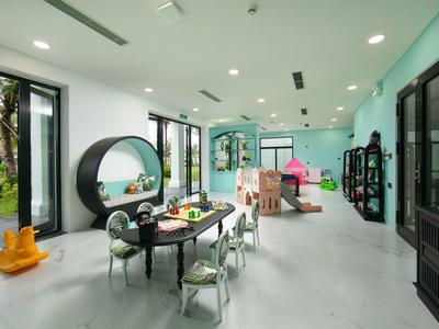 Lichte kinderspeelkamer met tafels, stoelen en speeltoestellen in een vriendelijke omgeving.