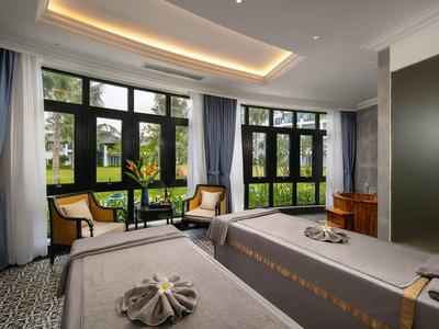 Lichte wellnessruimte met twee massagetafels, stoelen bij het raam en uitzicht op de tuin.