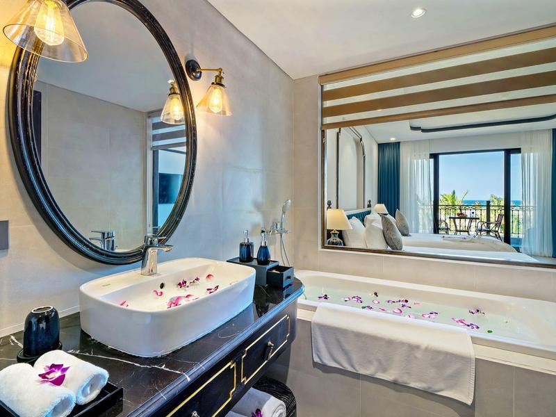 Moderne badkamer met wastafel, grote spiegel, bad en uitzicht op een terras.